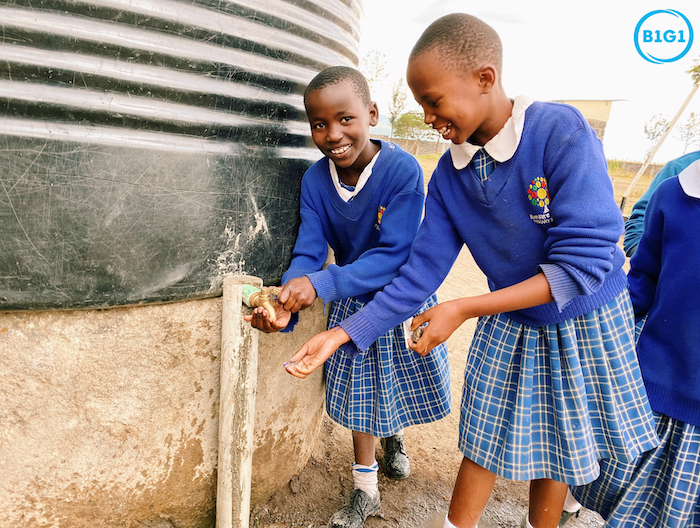 Two girls utilising the new water tap installed by B1G1